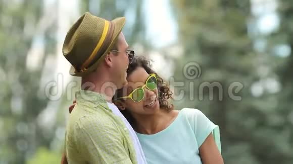 一对相爱的情侣在公园里笑着拥抱着她的手臂缠绕着他的脖子视频的预览图