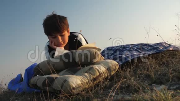 大自然中的一个男孩在夕阳下看书视频的预览图