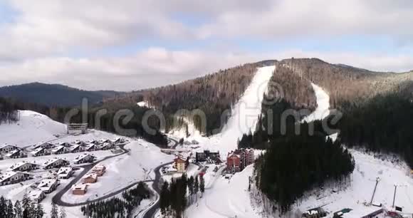 美丽的冬季小镇的鸟瞰山中央有滑雪坡缆车和视频的预览图
