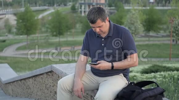 一个人坐在公园的绿色背景下一个陌生人偷走了他的包然后逃跑了视频的预览图
