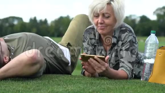 成熟的女人躺在公园的草地上视频的预览图