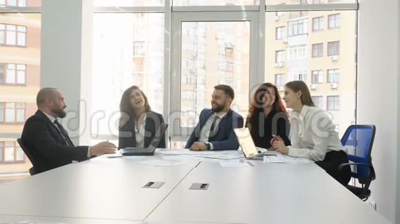 办公室工作人员一家大公司的员工两个年轻的男人和三个年轻的女人坐在一张桌子上讨论所有的事情视频的预览图