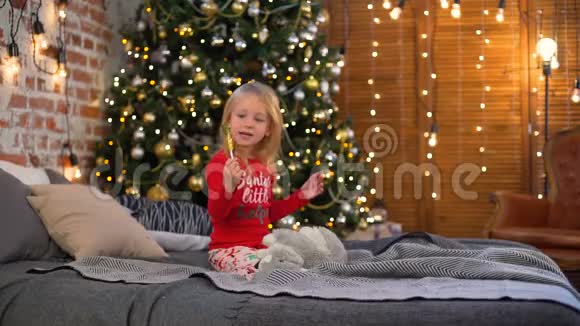 小女孩在圣诞树附近吃糖果视频的预览图