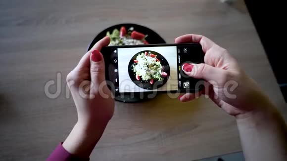 餐馆里的年轻女子用手机相机制作食物照片女人做沙拉的照片视频的预览图