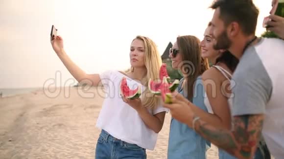 朋友吃西瓜站在沙滩上用智能手机相机自拍穿着视频的预览图