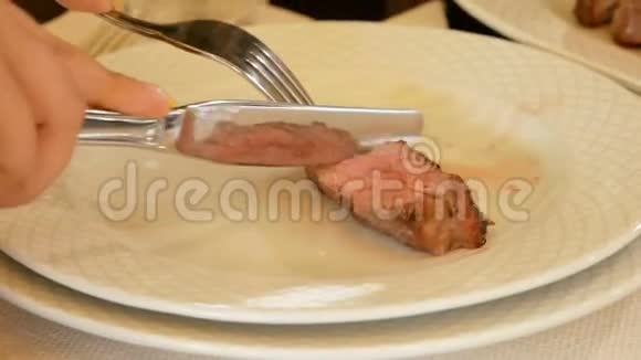 女性手拿刀叉切块肉排中烤盘这道菜反映在视频的预览图