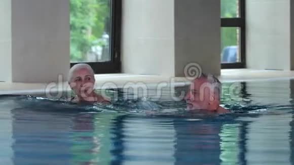 幸福的老年夫妇在室内酒店游泳池游泳视频的预览图