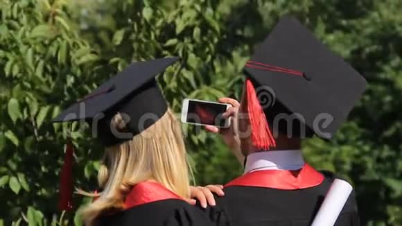 毕业典礼结束后穿着学术服装的朋友用手机拍照视频的预览图