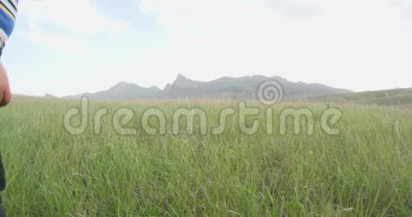 男孩来到山坡上站在房子和山谷前面城镇在草地上视频的预览图