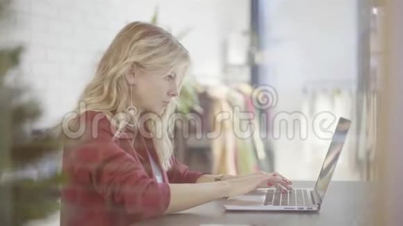 年轻的女经理在一家小服装店的笔记本电脑上打字视频的预览图