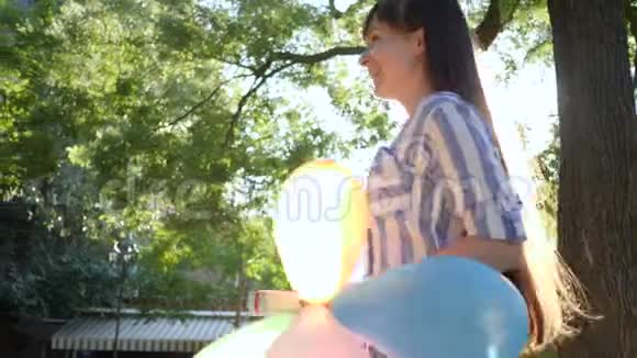 带着五颜六色气球的女孩在公园里送礼物和拥抱女朋友情感视频的预览图