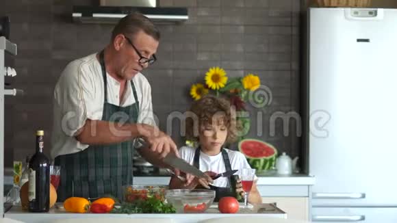 老人给男孩一把菜刀教你如何切黄瓜祖父和孙子在厨房里视频的预览图