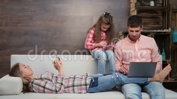 家庭在沙发上忙于电子设备视频的预览图