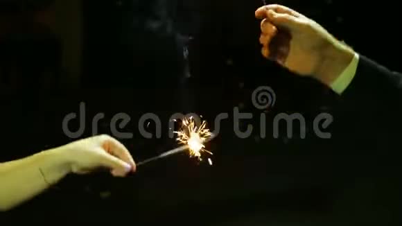 一男一女在黑色背景下用孟加拉蜡烛烟花庆祝圣诞新年视频的预览图