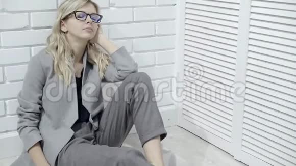 戴眼镜的金发美女坐在地板上视频的预览图