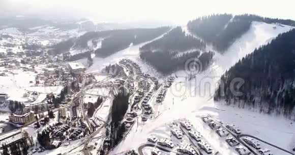 美丽的冬季小镇的鸟瞰山中央有滑雪坡缆车和视频的预览图