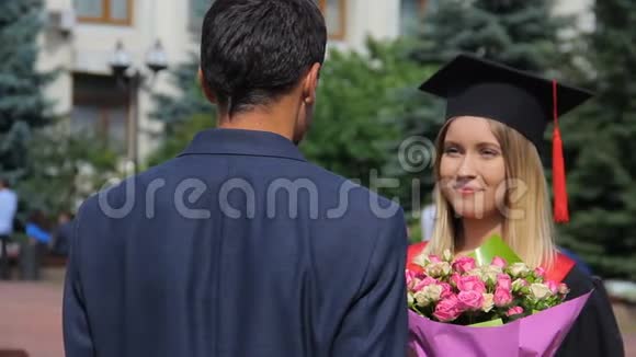 穿西装的男人祝贺他毕业的女朋友并献上鲜花视频的预览图
