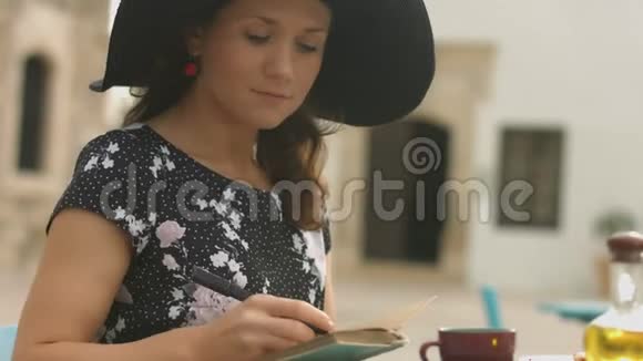 启发年轻女士在记事本上写笔记喜欢街头咖啡馆视频的预览图