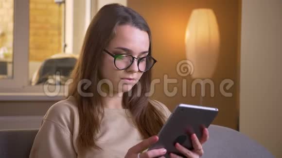 用平板电脑为年轻有魅力的白种人女性戴上眼镜并在镜头中显示绿色屏幕视频的预览图