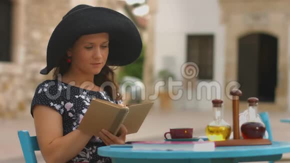 漂亮的女人在咖啡馆里读旧纸书享受休息放松度假视频的预览图