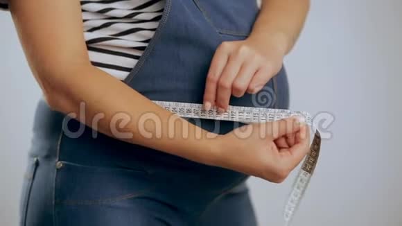 孕妇站在白色背景下测量腹部视频的预览图