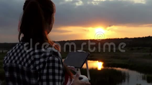 好女人在日落时用面板控制无人机视频的预览图