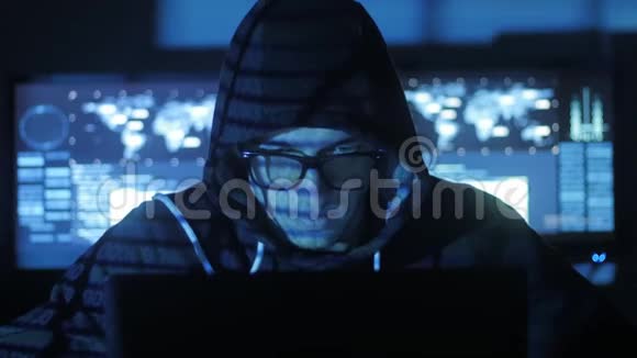 戴着眼镜在电脑上工作的黑客而蓝码字符则在电脑上反射他的脸视频的预览图