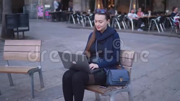 优雅的年轻女子坐在户外的城市广场上视频的预览图