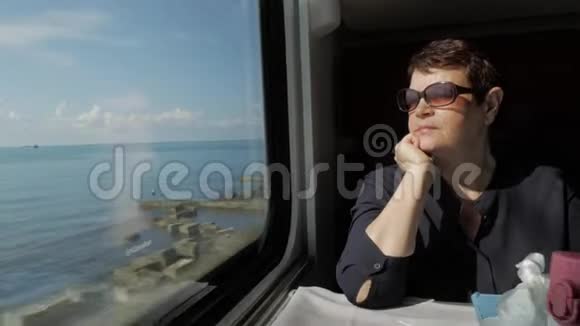 火车窗口附近戴墨镜的老年妇女视频的预览图