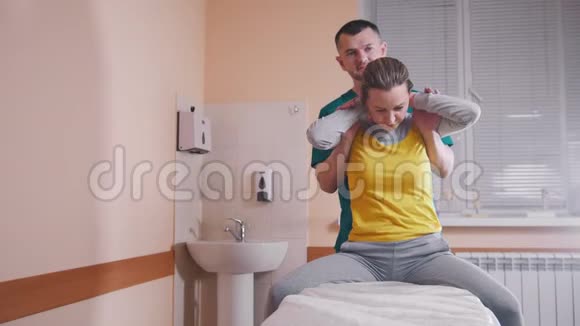 手动治疗师按摩和检查一个年轻的女人伸展她的背部视频的预览图
