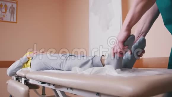 手动治疗师按摩和检查躺在按摩台上的年轻妇女视频的预览图