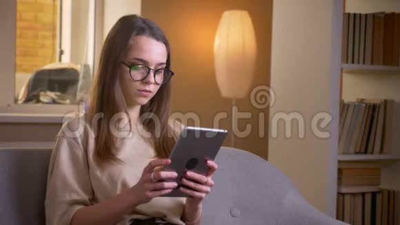 用平板电脑为年轻有魅力的白种人女性在眼镜中的特写肖像并显示绿色的色度屏幕以显示视频的预览图