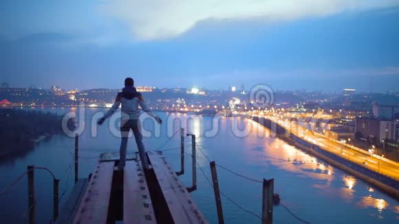自由男人举起双手站在桥上欣赏城市令人惊叹的夜景视频的预览图