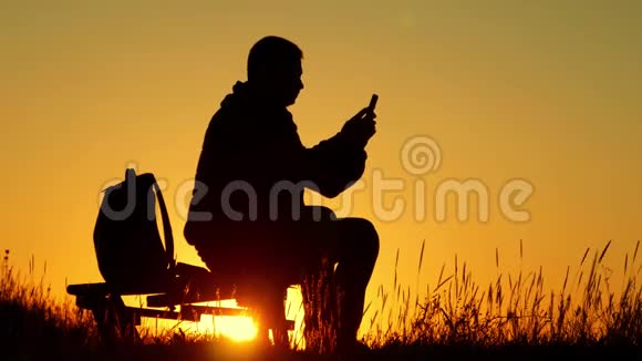 一个带背包的年轻游客用手机拍照在夕阳下旅行概念视频的预览图