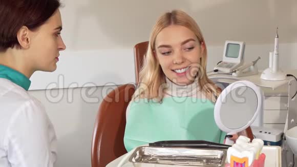 快乐的美女在牙科诊所用镜子检查牙齿视频的预览图