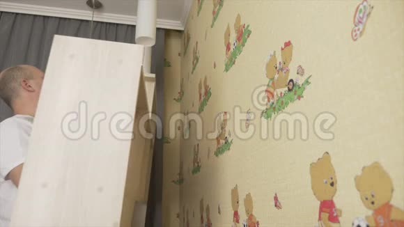 成人白种人将书架挂在儿童房的墙上秃子把书架挂在儿童房里DIY概念视频的预览图