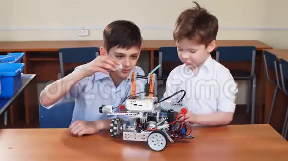 两个兄弟的孩子在学校机器人课上玩机器人玩具室内视频的预览图