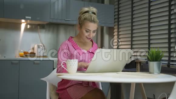 兴奋的女人在厨房里用笔记本电脑视频的预览图