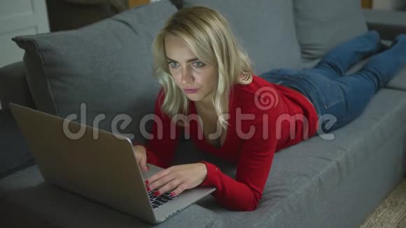 有笔记本电脑的严肃女人躺在沙发上视频的预览图