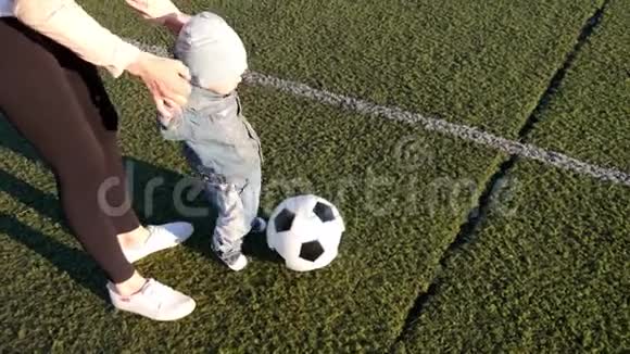 小男孩和他妈妈在足球场上踢足球视频的预览图