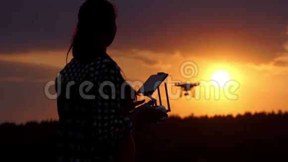 不错的女人在日落时用面板控制无人机视频的预览图