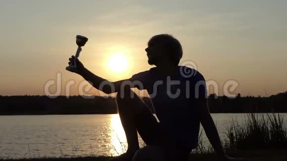 男人崇拜他的冠军碗坐在斯洛莫的湖岸上视频的预览图