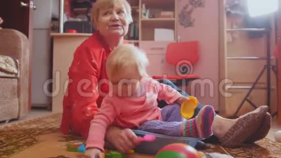 小女孩和她的祖母玩玩具温柔地坐在地板上交流视频的预览图
