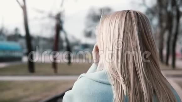 慢动作的女人边走边整理头发年轻的白种人金发20多岁穿着蓝色温暖的外套和围巾拍摄视频的预览图