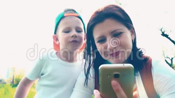 妈妈和儿子一起在城市公园的智能手机里看着一些东西妈妈和儿子微笑着视频的预览图
