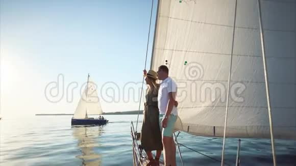 在阳光明媚的日子里年轻夫妇站在帆船的鼻子上望着大海视频的预览图