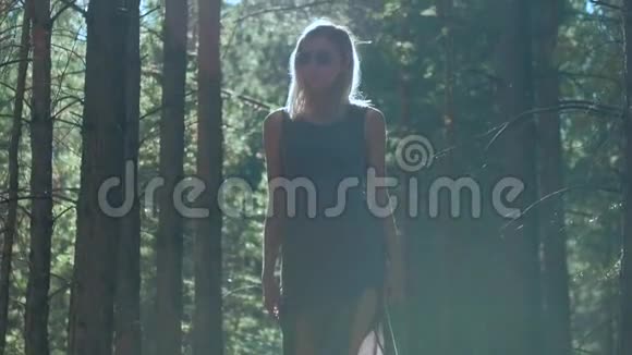 苗条的金发女郎走在树林里视频的预览图