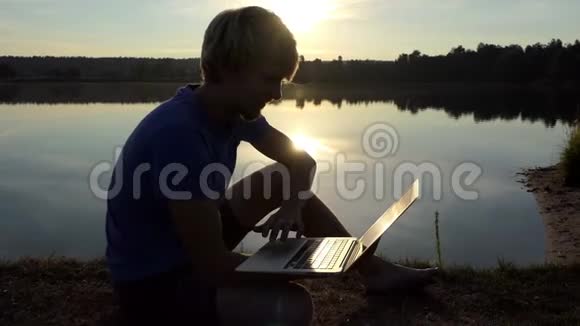 聪明的人在slomo的一个湖岸用他的笔记本电脑工作视频的预览图