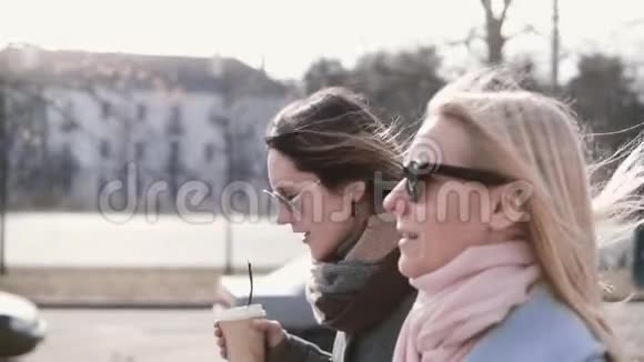 慢动作白种人女孩走路聊天漂亮的女士穿着时尚的保暖外套和太阳镜在街上说话视频的预览图