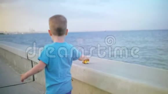 小男孩在海边的桥栏杆上玩玩具车视频的预览图
